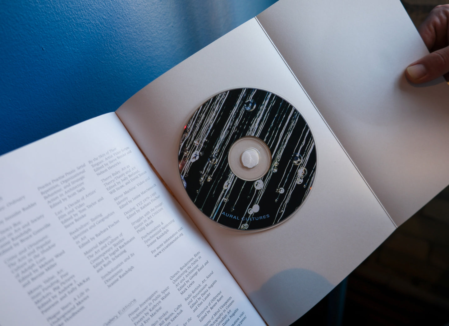 CD on top of an open book with a blue surface underneath