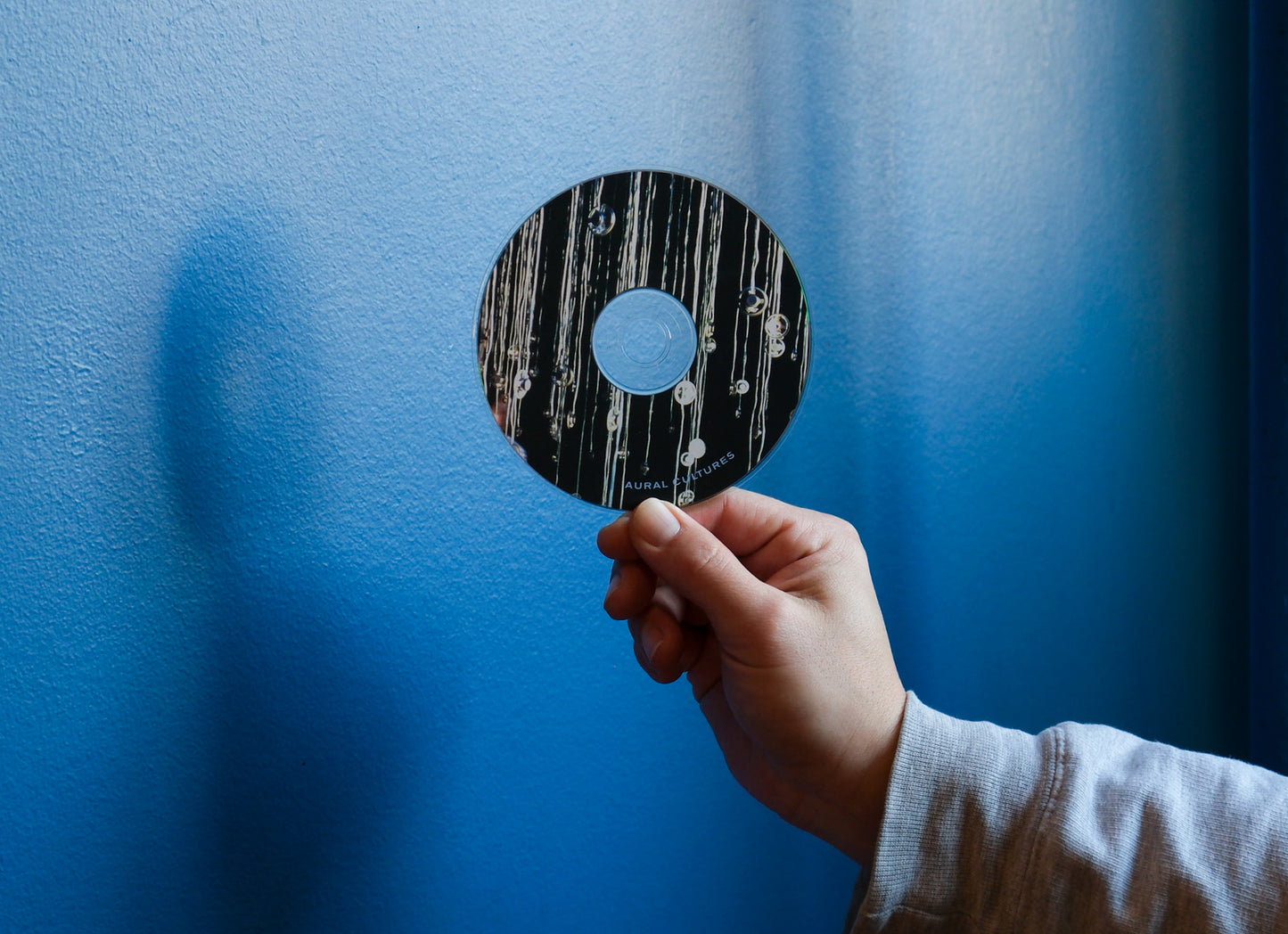 Hand holding a vinyl record against a blue background