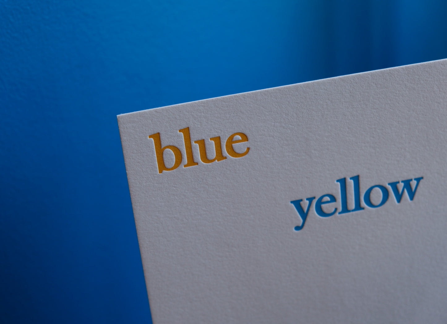 Letterpress printed card with 'blue' in gold and 'yellow' in blue on a blue background