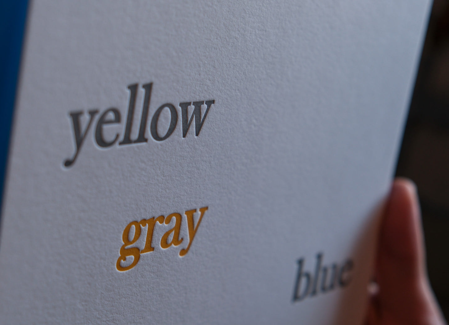 Letterpress printed card with the words 'yellow', 'gray', and 'blue' text on a gray background