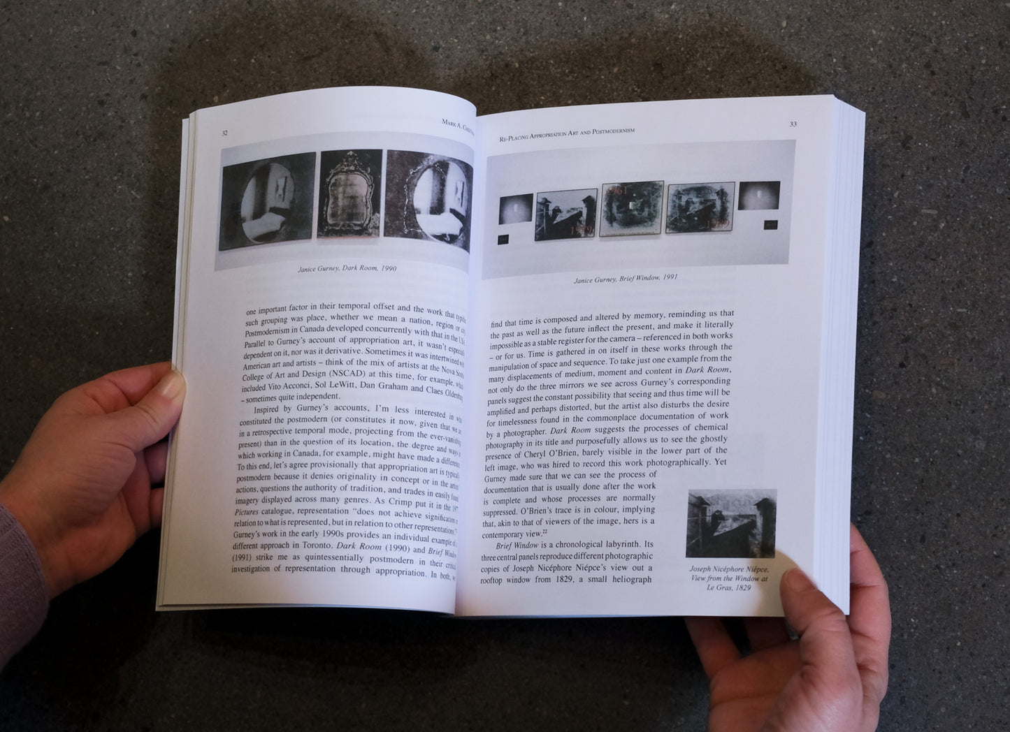 Open book held by a person with text and images on a dark surface