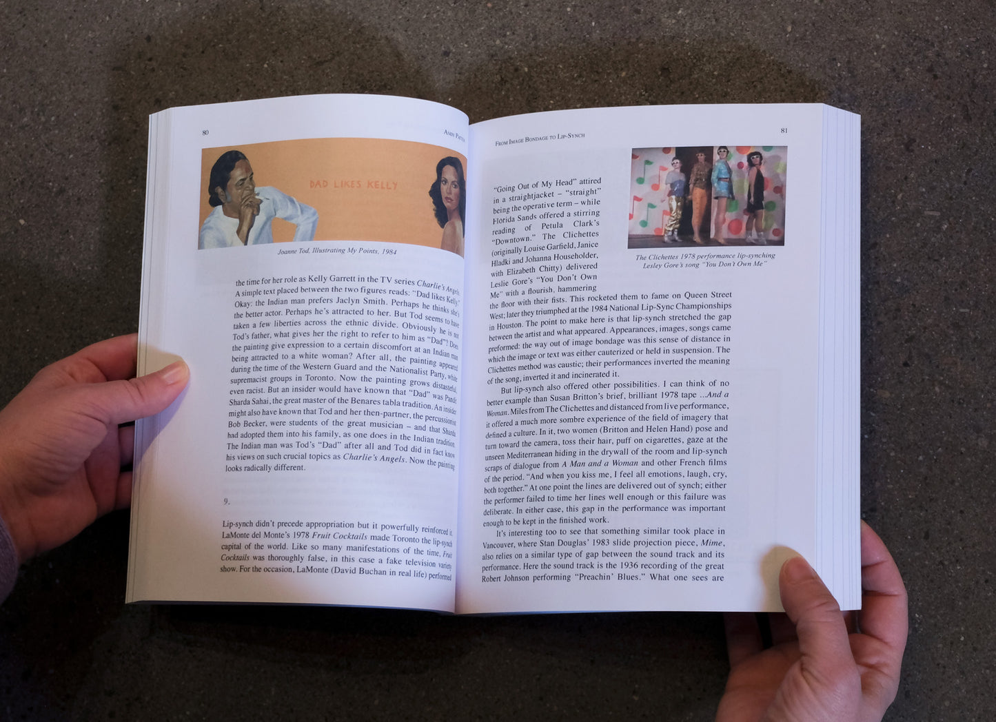 Open book held by a person with text and images on a dark surface