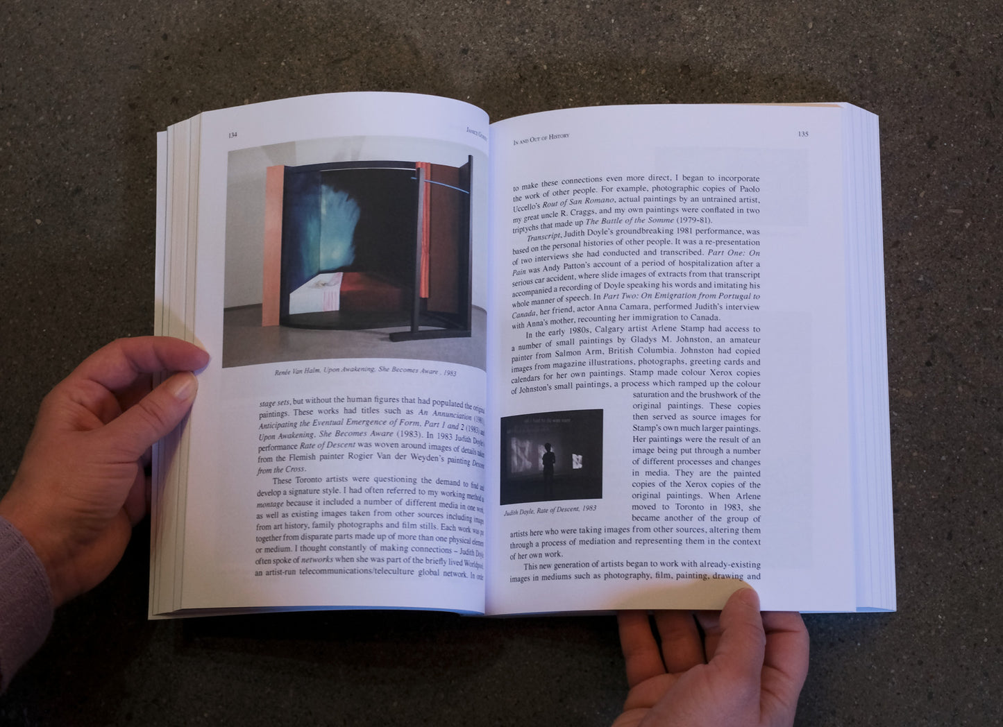 Open book with text and images held by a person on a dark surface