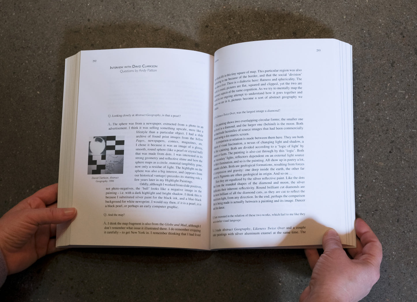 Open book held by hands on a textured surface