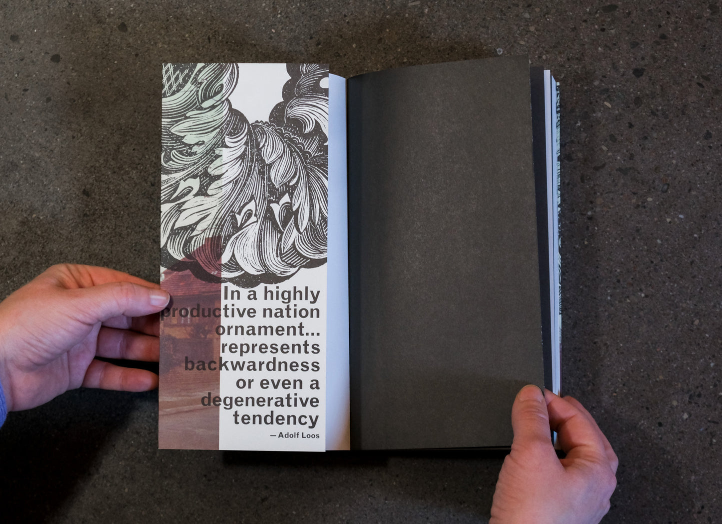 Open book held by hands with text and illustration on a dark surface