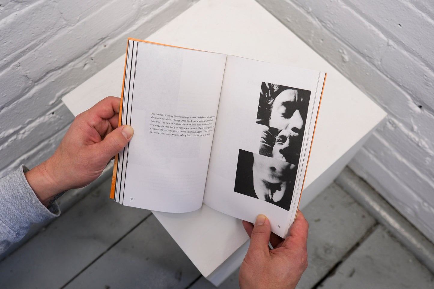 Person holding an open book with black and white photographs on a gray surface