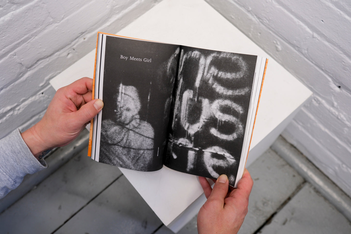 Open book held by a person with black and white pages on a light gray surface.