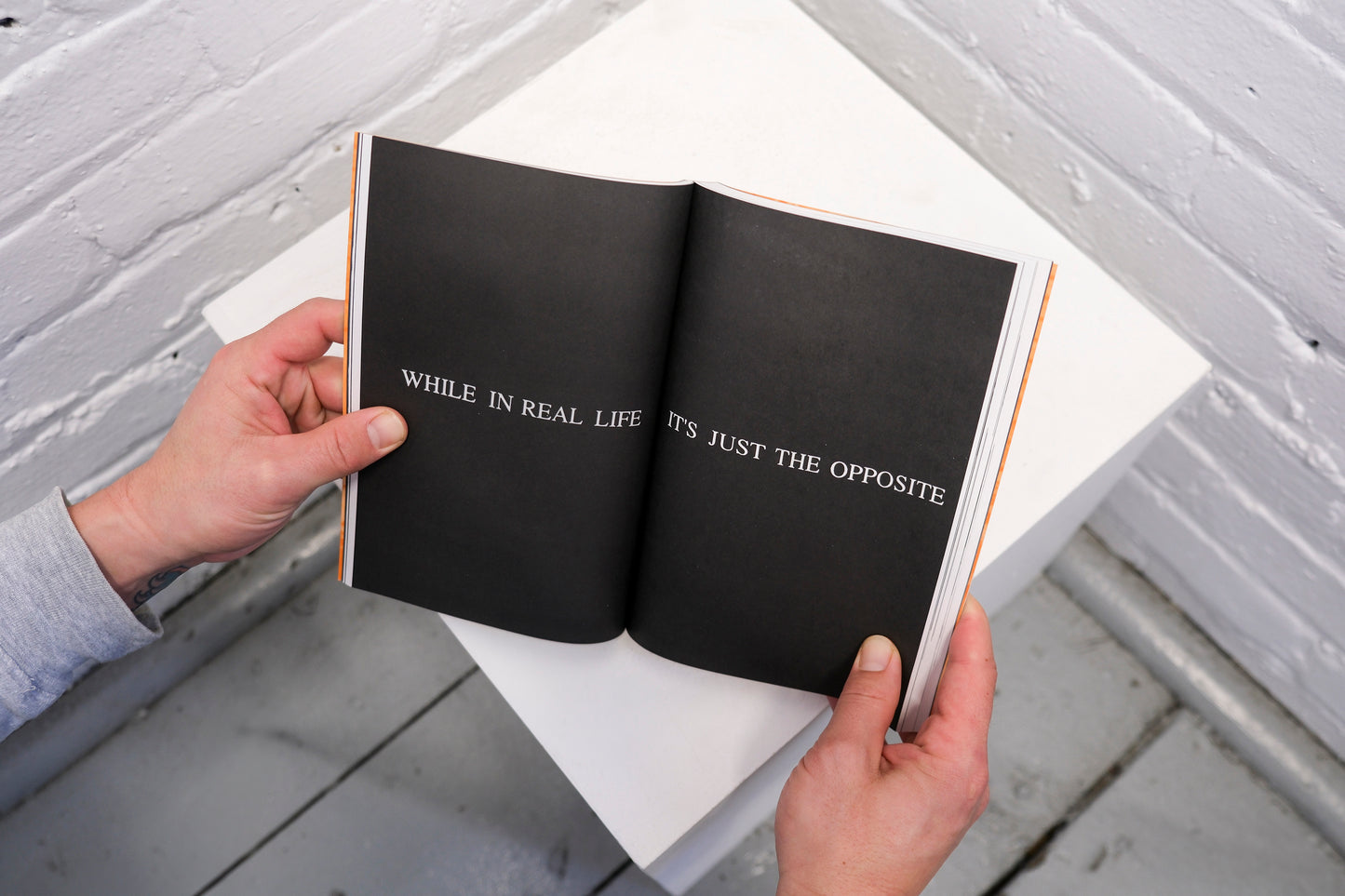 Open book held by hands with text on a white surface