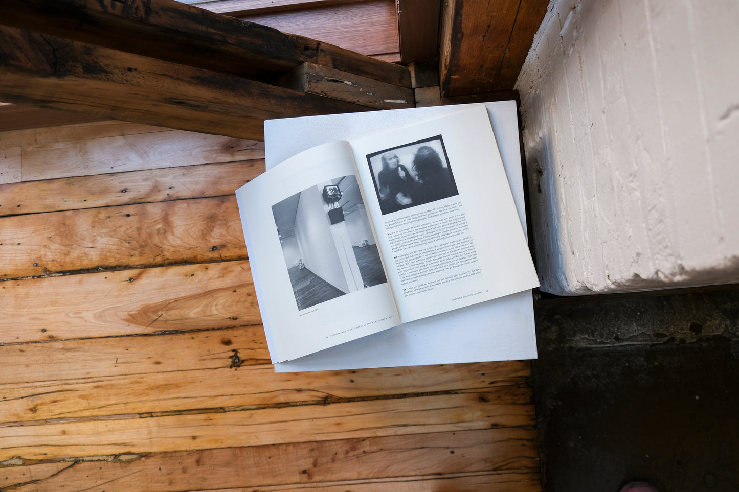Open book with black and white photos on a plinth on a wooden surface
