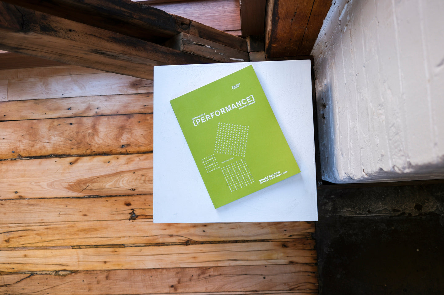 Green book titled 'PERFORMANCE!' on a white surface with wooden background