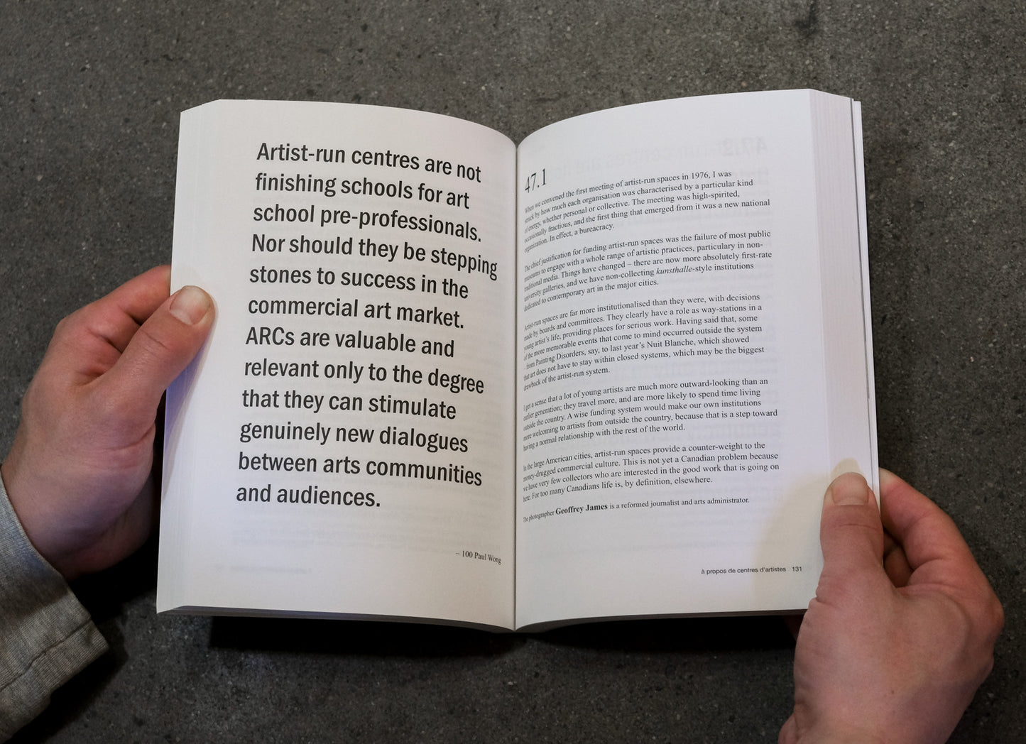 Open book held by hands with text on a dark surface