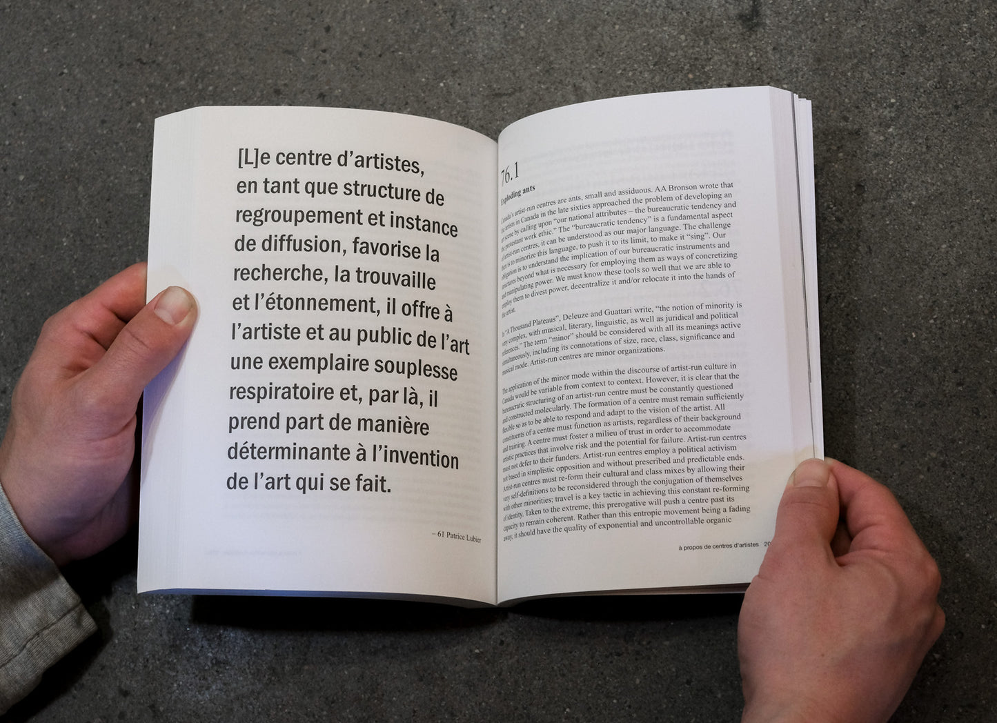 Open book held by hands on a dark surface with text visible