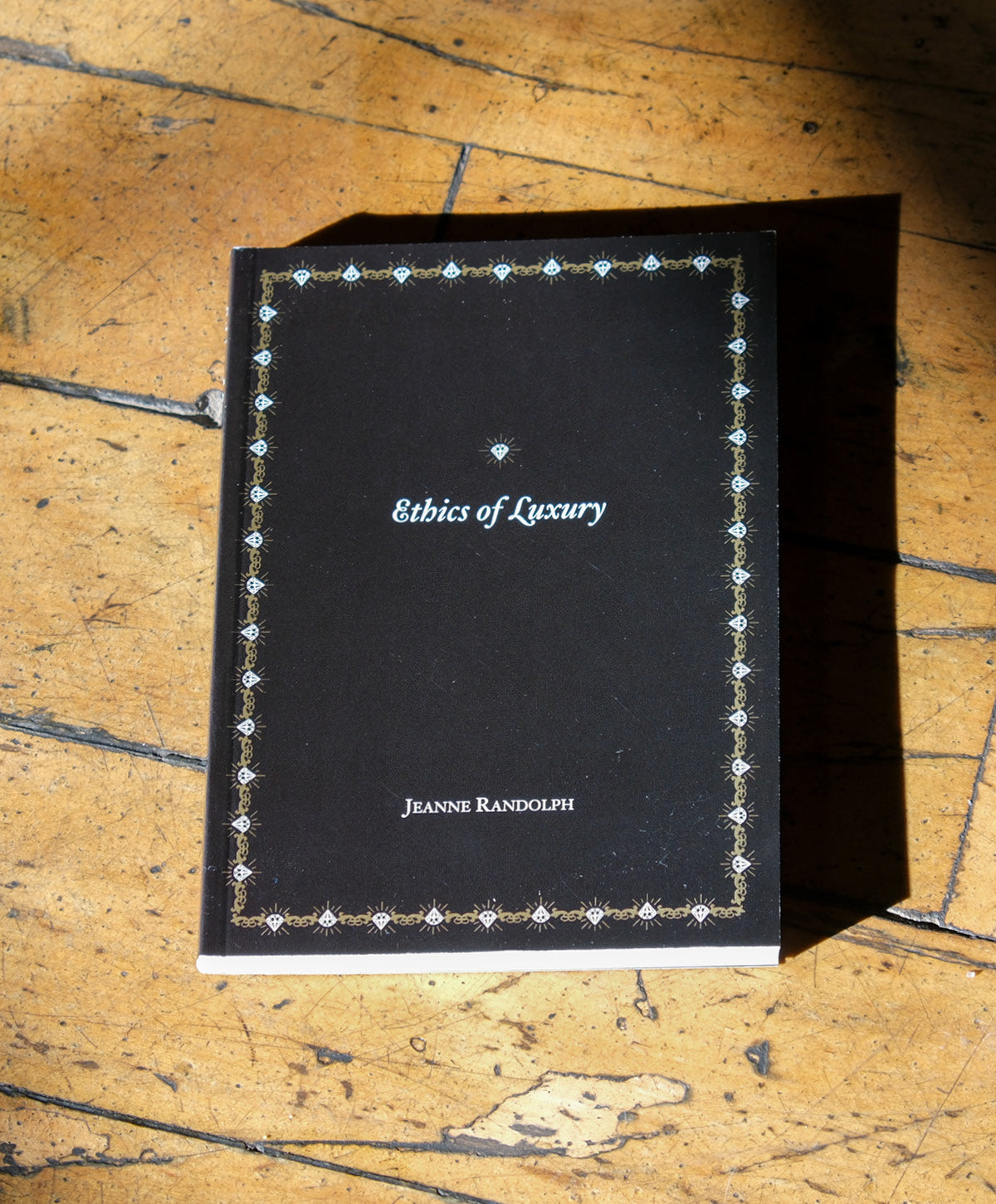Black book titled 'Ethics of Luxury' by Jeanne Randolph on a wooden surface