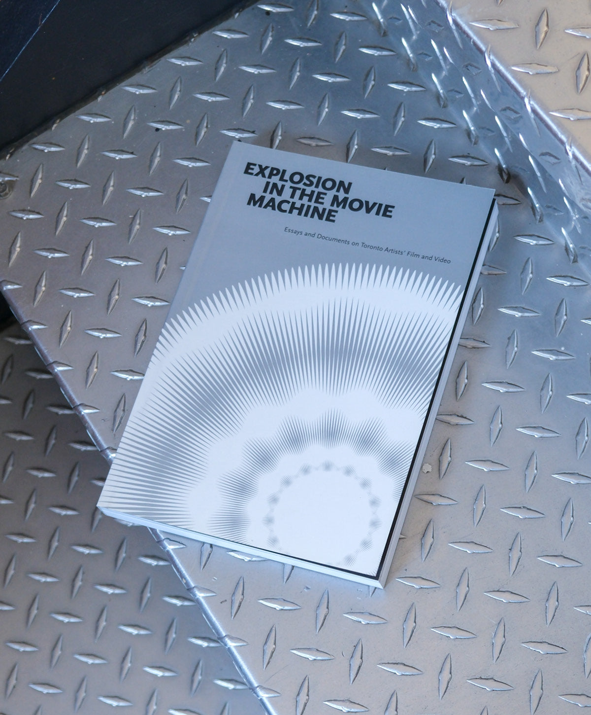 Book titled 'Explosion in the Movie Machine' on a metallic surface