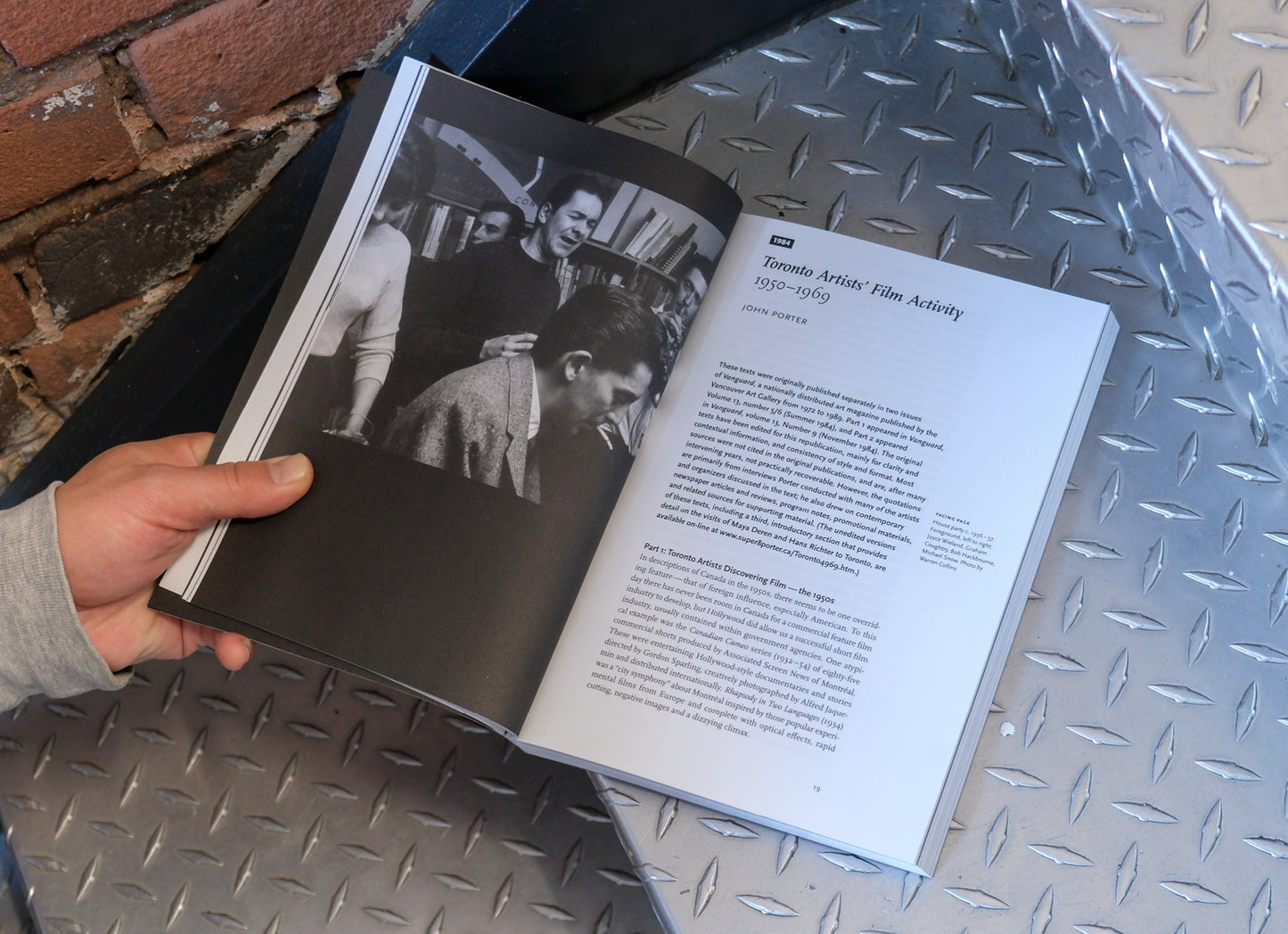 Open book with black and white photos and text on a metal surface.