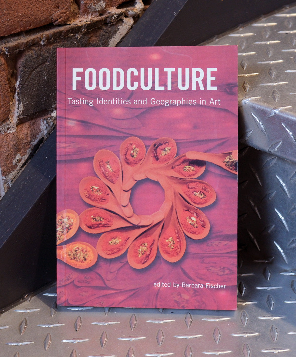 Book titled 'Foodculture' on a metal surface with a brick wall background
