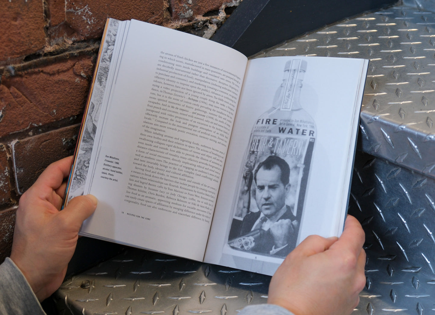 Person holding an open book with a black and white photo on a metal surface.