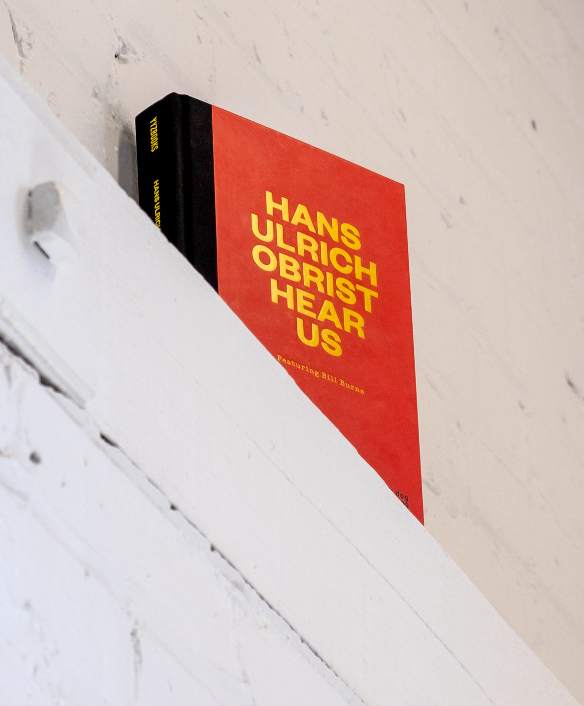 Hans Ulrich Obrist Hear Us cover on a brick ledge painted white