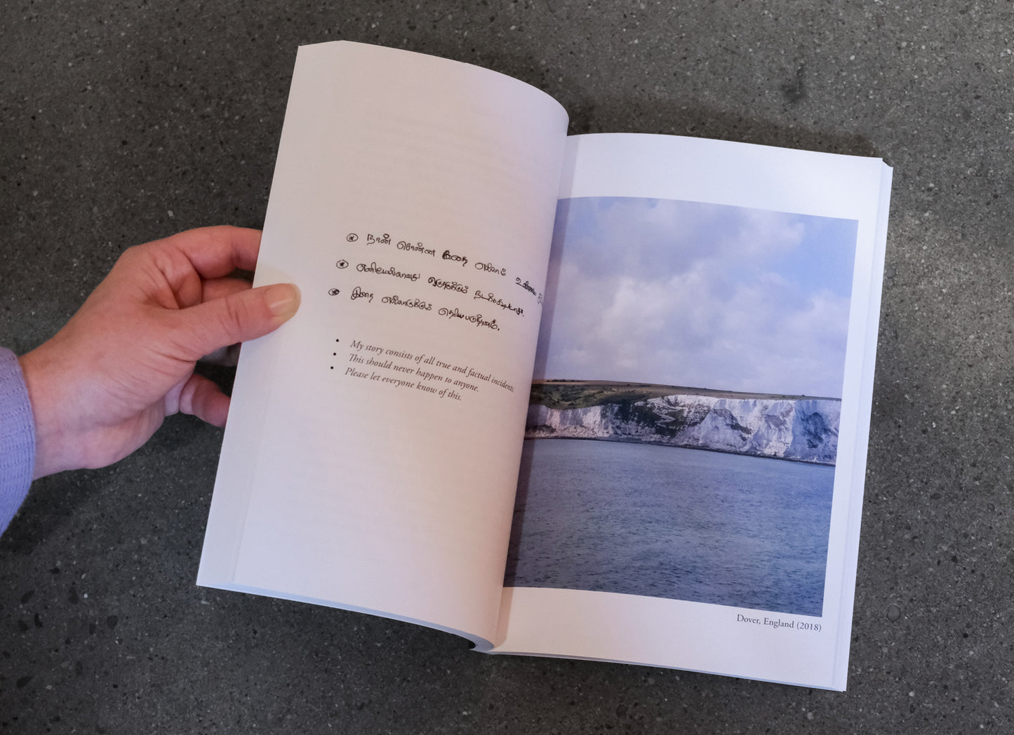 Open book with a photograph of a coastal scene on a dark surface
