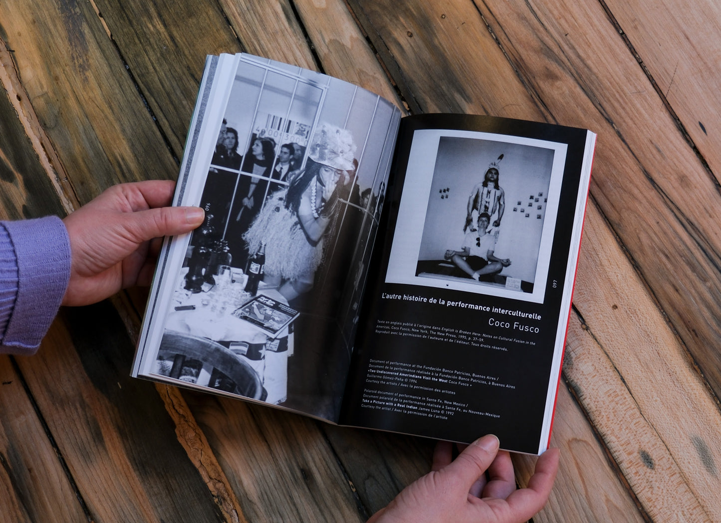 Open book with black and white photos on a wooden surface and hands holding it open