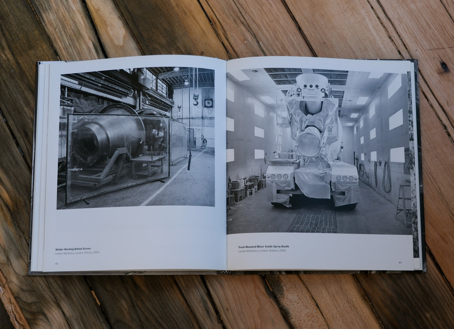 Open book showing black and white photographs of a large vehicle on a wooden surface