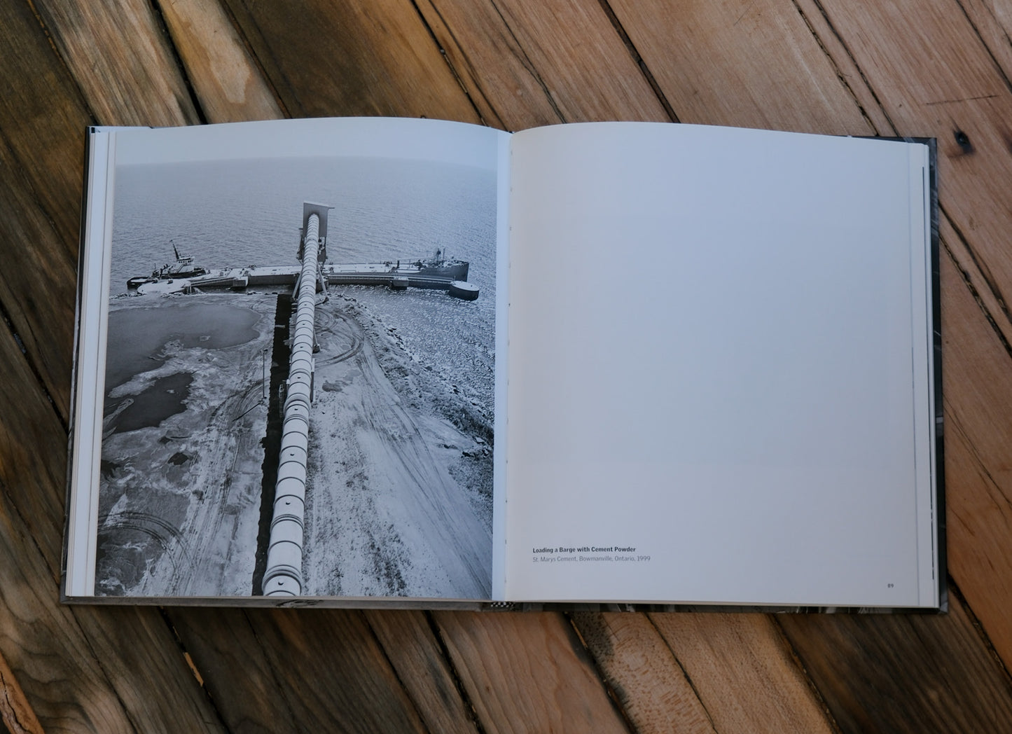 Open book showing a black and white photograph of a large pipe on a wooden surface