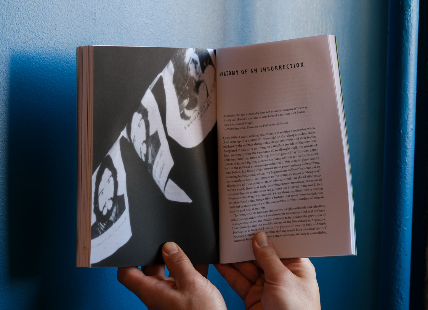 Open book held against a blue wall