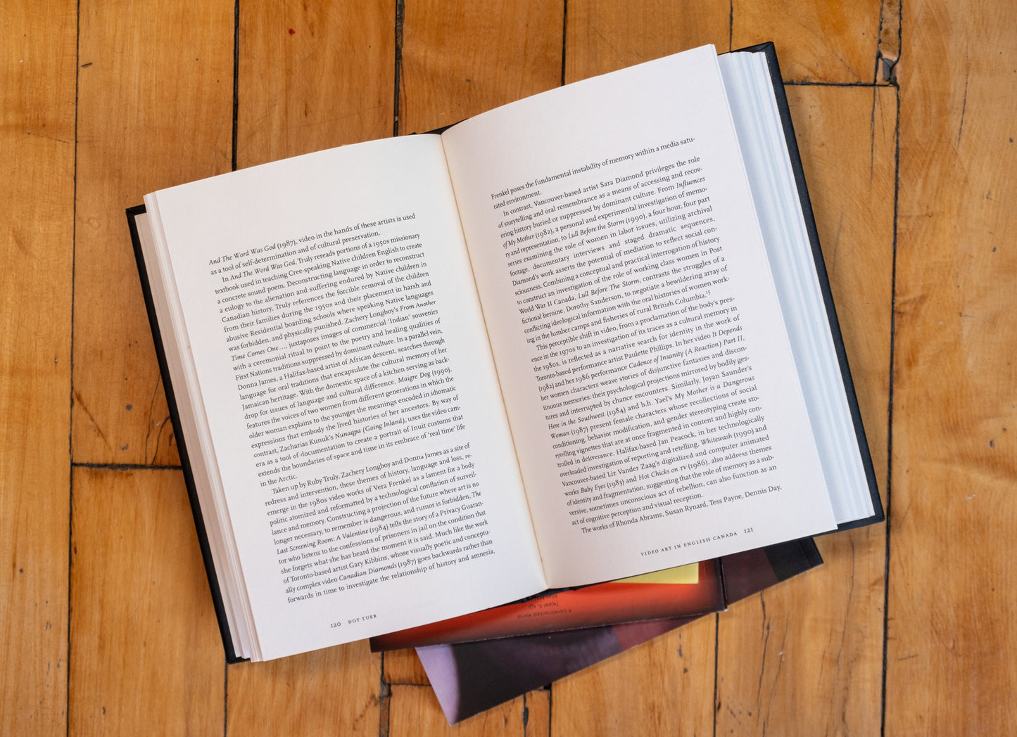 Mirror Machine: Video and Identity opened to show pages on a stack of books on a wood floor