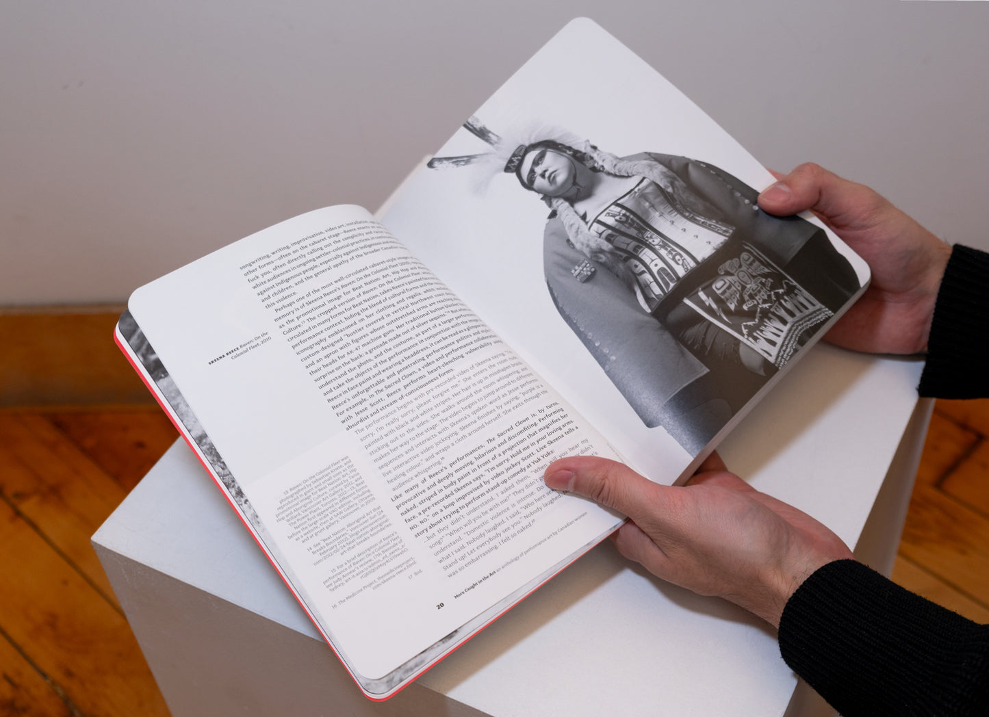 Hands holding More Caught in the Act: An Anthology of Performance Art by Canadian Women opened on plinth to show pages