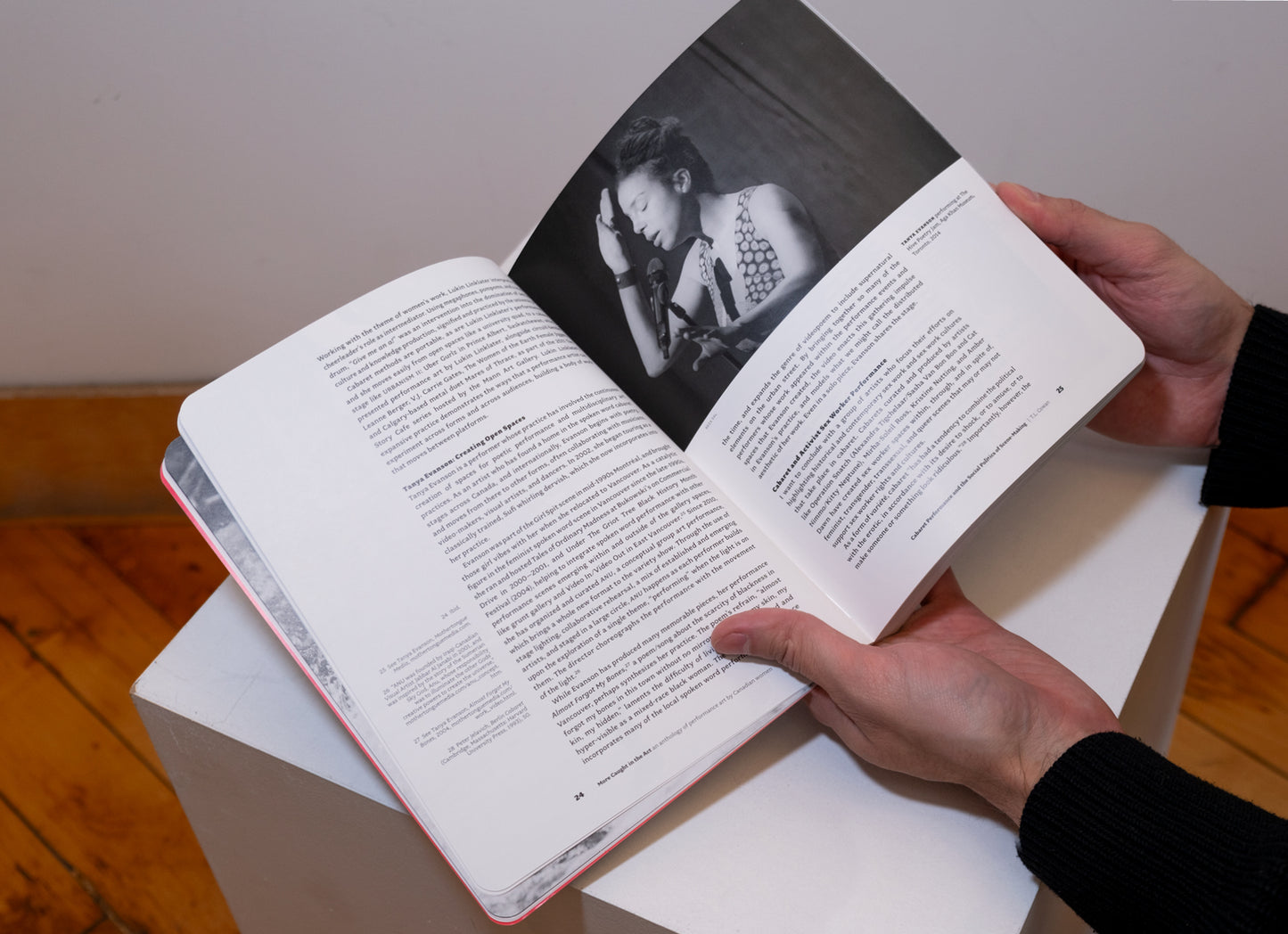 Hands holding More Caught in the Act: An Anthology of Performance Art by Canadian Women opened on plinth to show pages