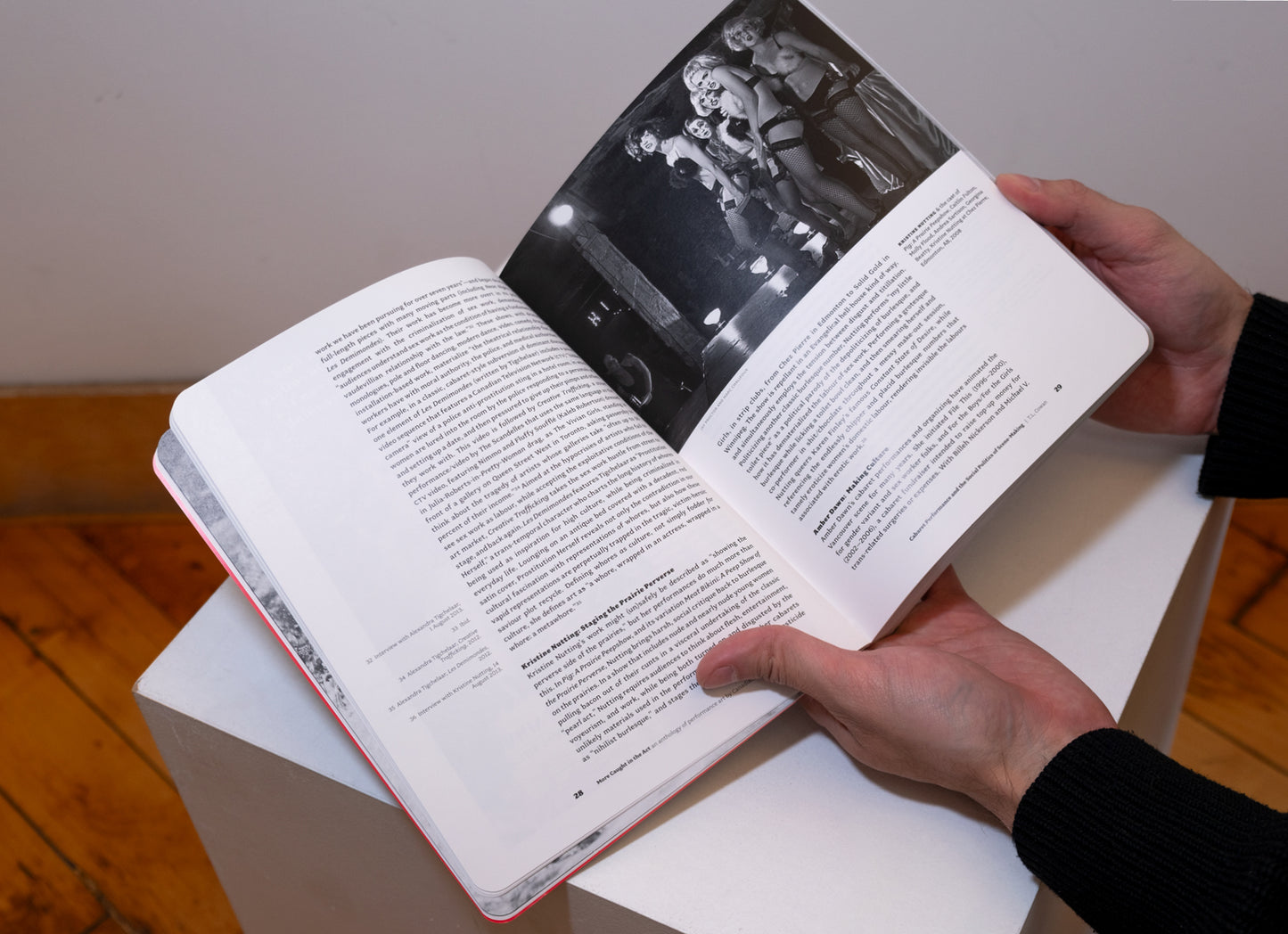 Hands holding More Caught in the Act: An Anthology of Performance Art by Canadian Women opened on plinth to show pages