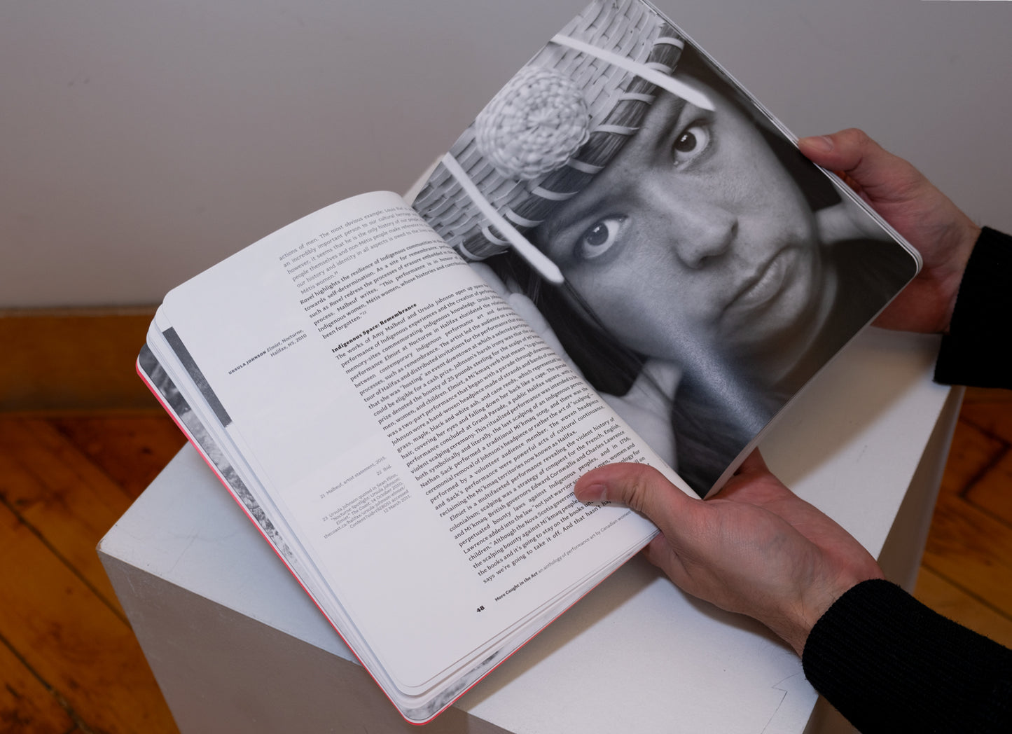 Hands holding More Caught in the Act: An Anthology of Performance Art by Canadian Women opened on plinth to show pages