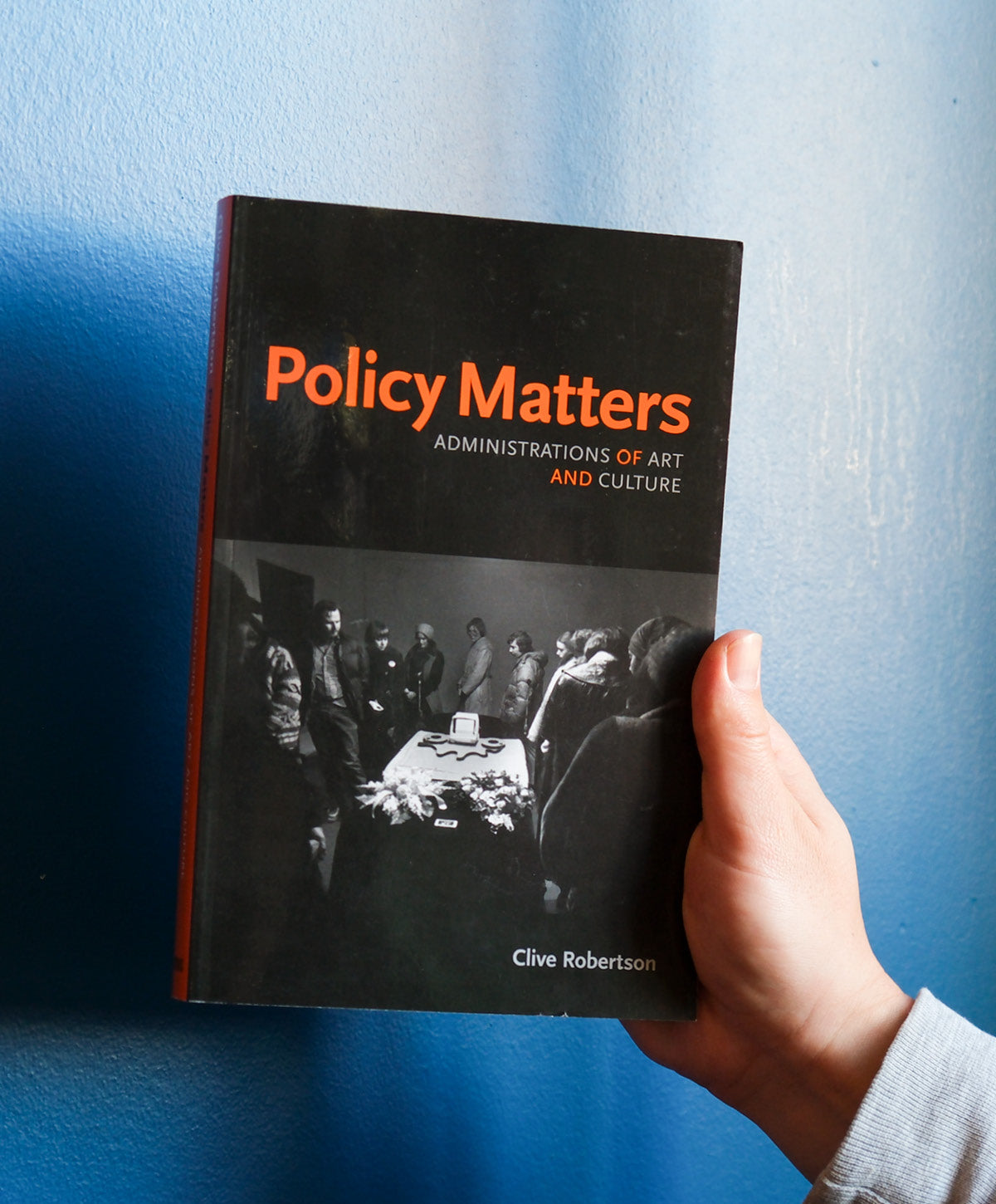 Book titled 'Policy Matters' held by a hand against a blue background