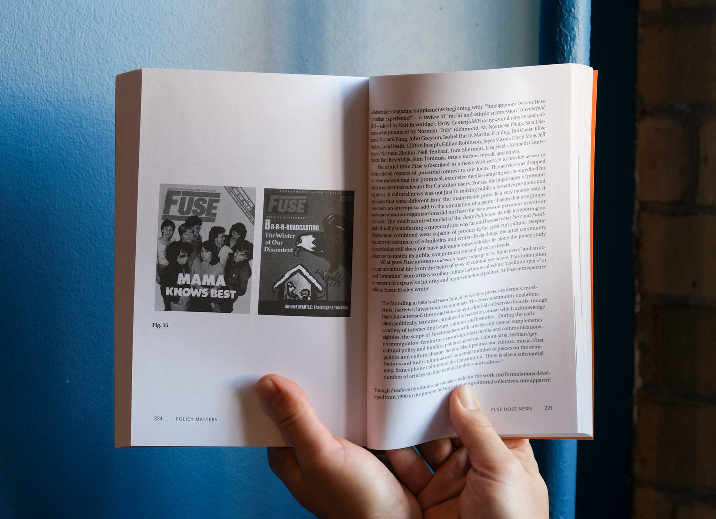 Open book held by a hand with visible text and images on a blue background