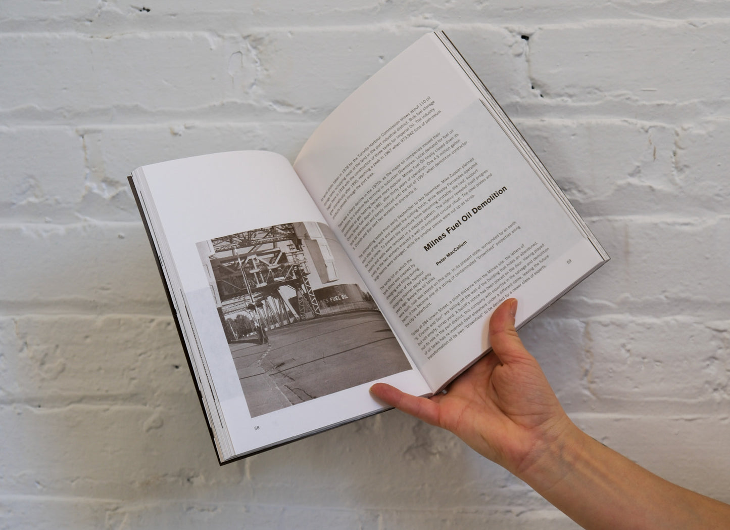 Open book with black and white photo and text on a white brick wall background