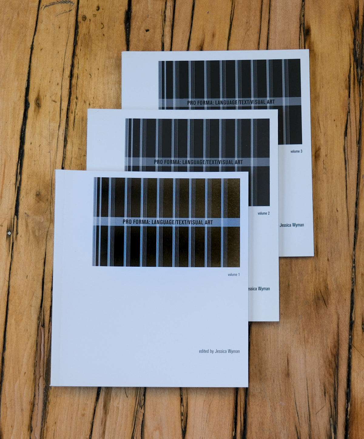 Three books with a bar code design on a wooden surface