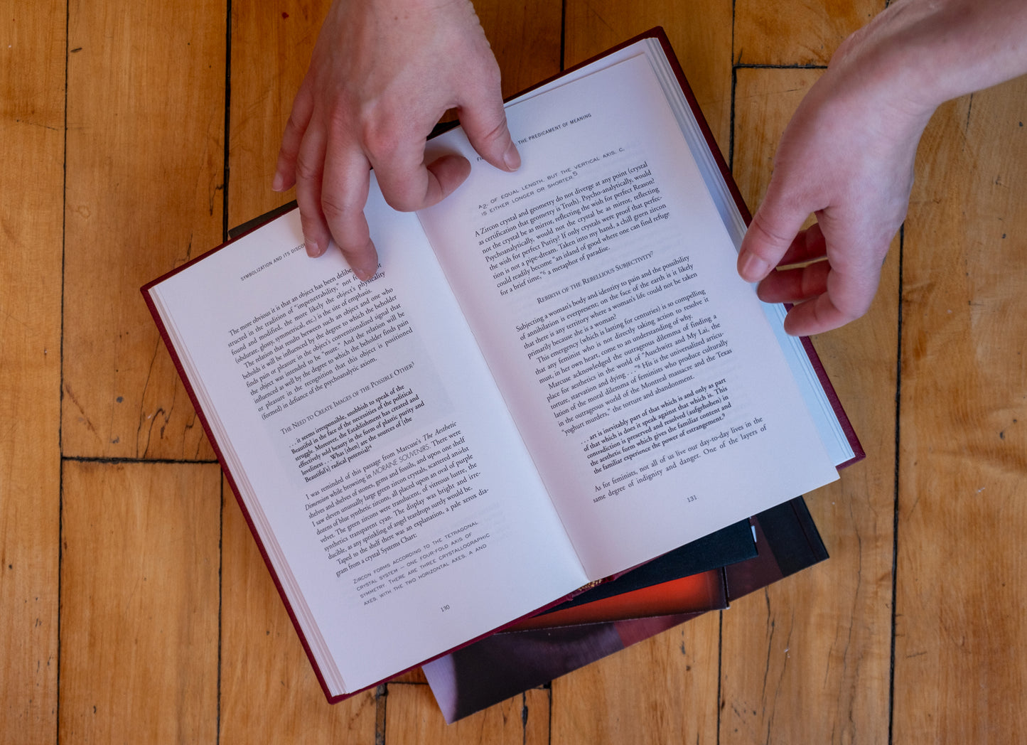 Open book on a wooden surface with hands turning a page