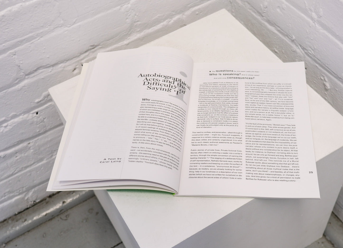 Open book on a white surface with a light gray brick wall background